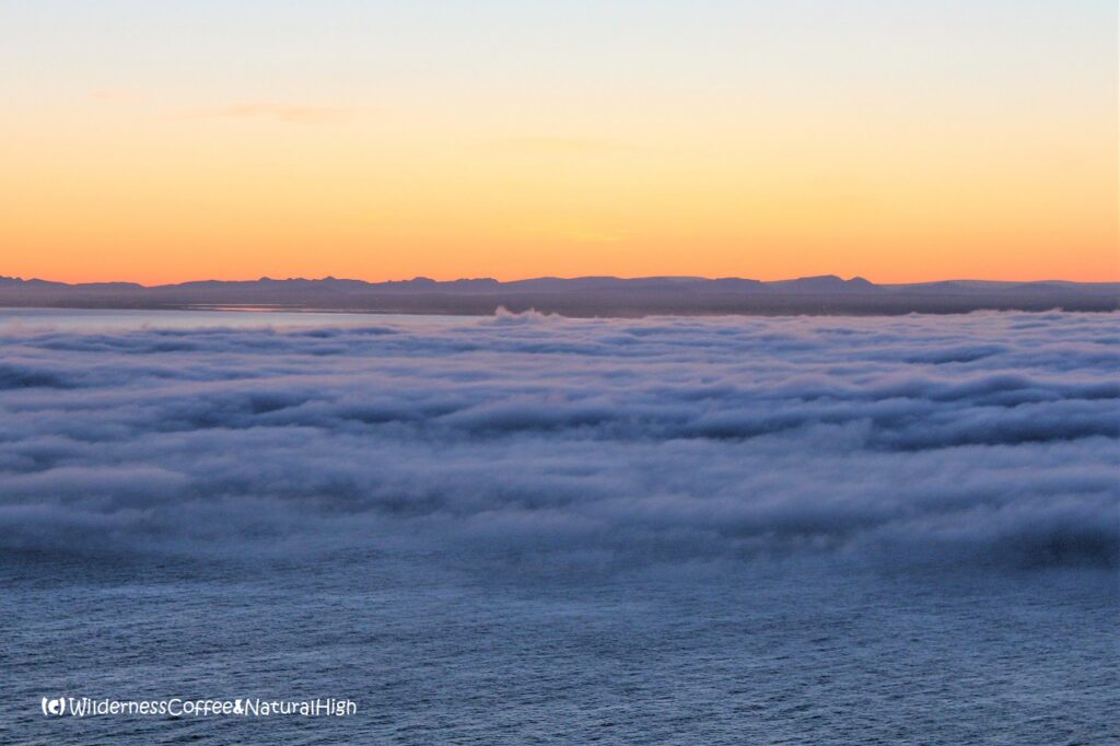 Sea fog and midnight sunset Dalalæða moving in over the sea, Heimaey, Vestmannaeyjar, Iceland.